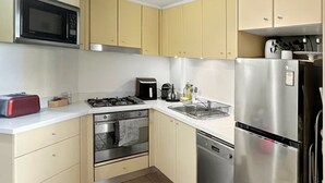 Una cocina compacta equipada con microondas, estufa, horno, lavavajillas y un refrigerador de acero inoxidable.