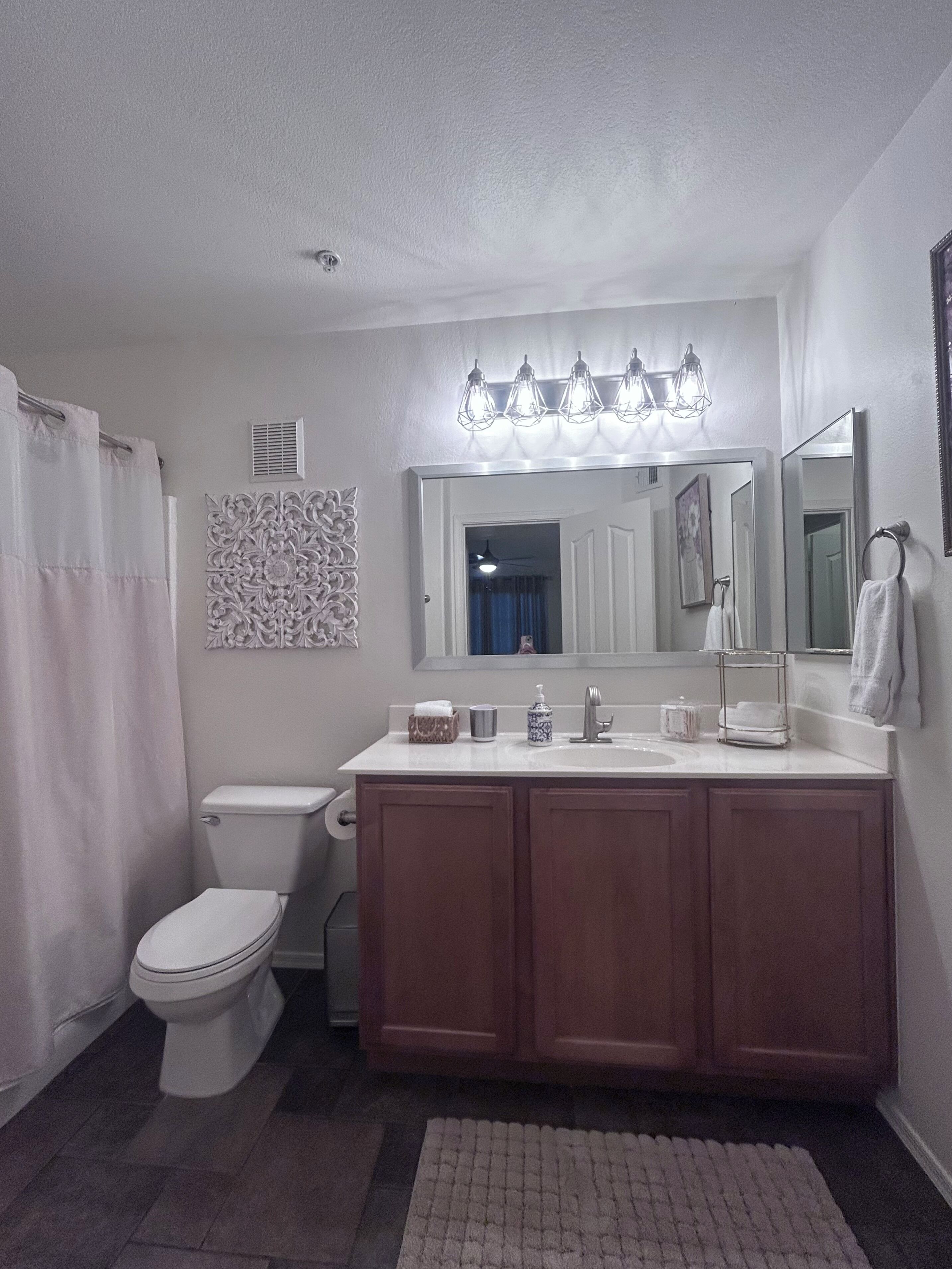 Un baño con inodoro, lavabo, tocador y cortina de ducha.