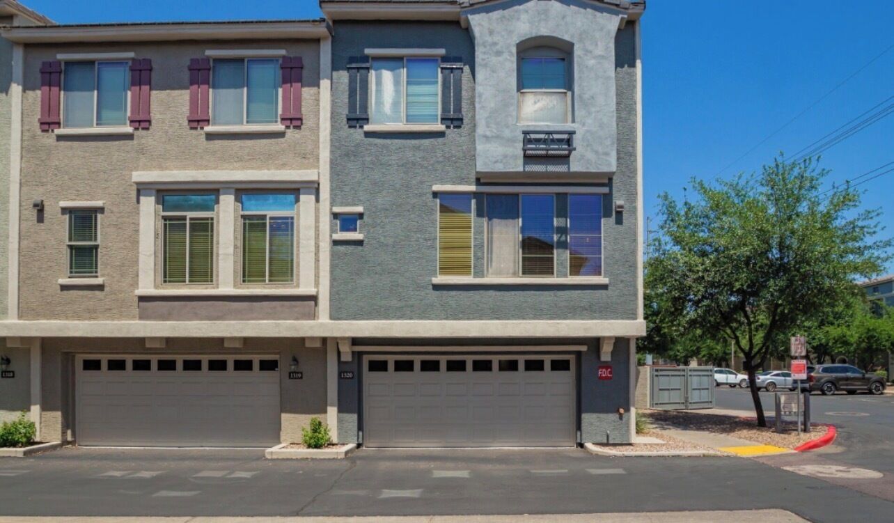 A two-story residential building with a garage, a balcony, and a small porch area.