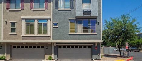A two-story residential building with a garage, a balcony, and a small porch area.