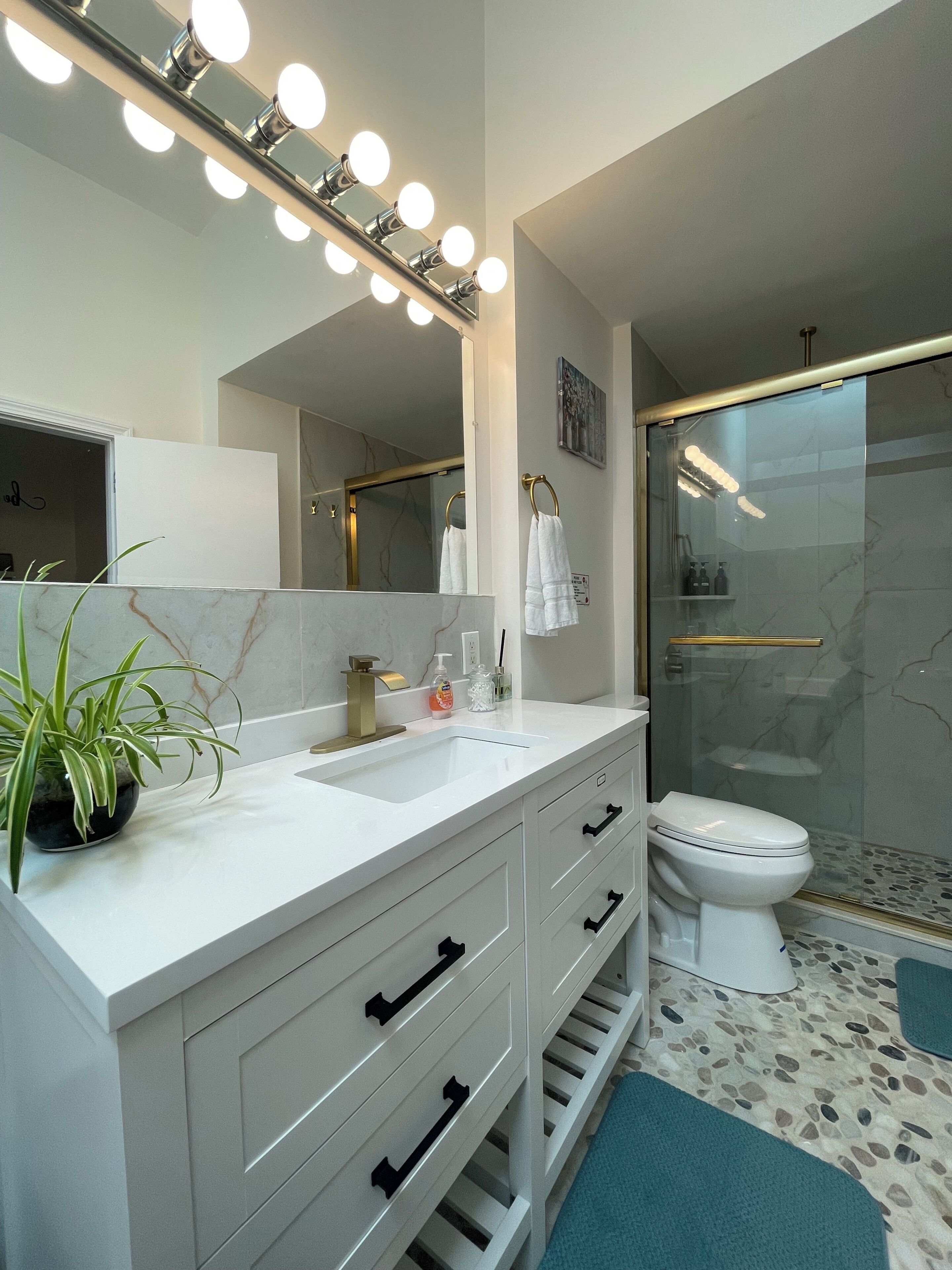 A modern bathroom with a vanity, sink, mirror, and a shower area.