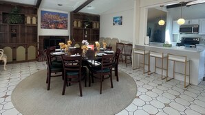 Un espace repas comprenant une table ronde, des chaises et un tapis central. Il y a également un coin cuisine avec un four à micro-ondes et un comptoir-bar.