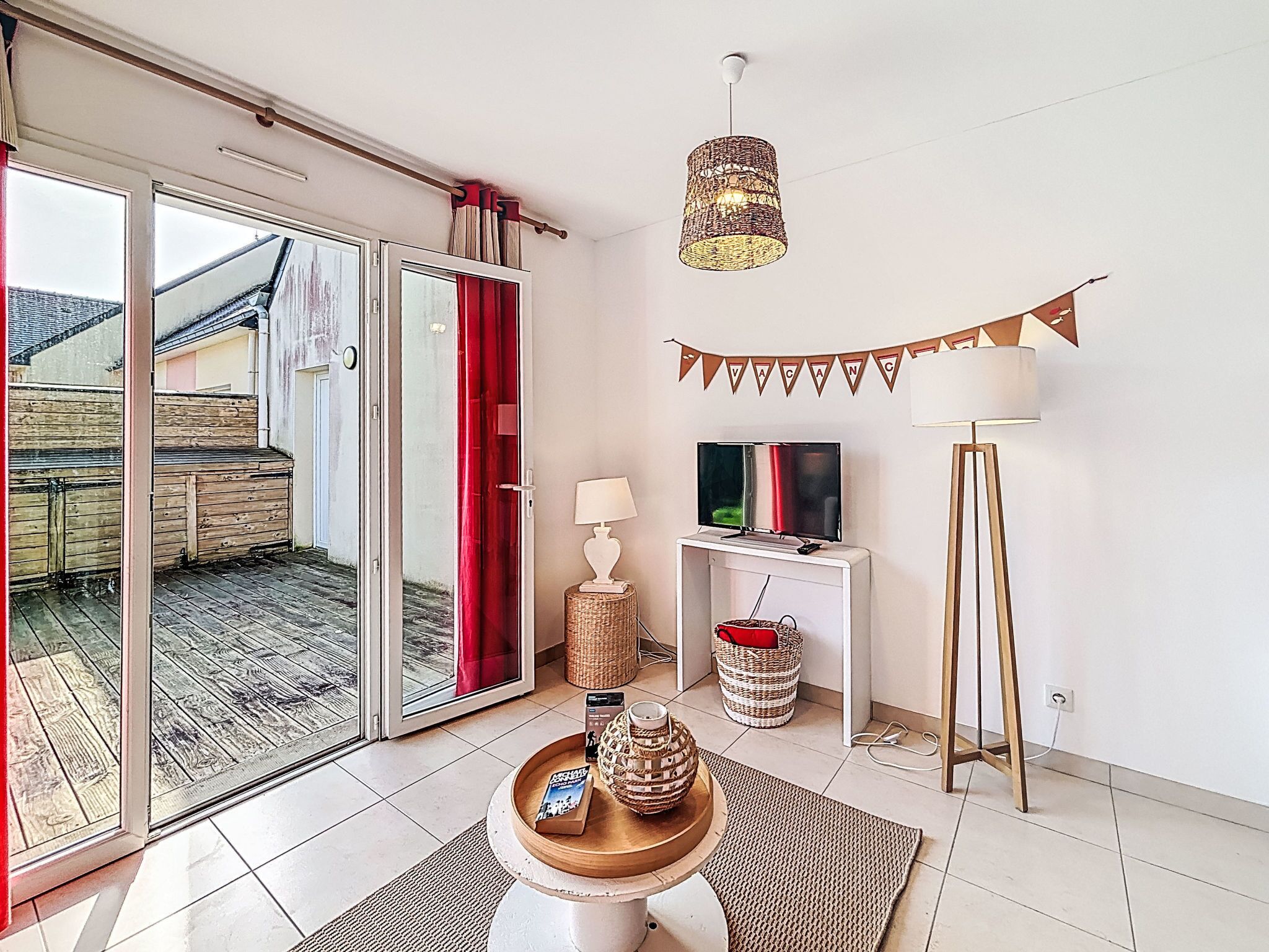 Ein modernes Wohnzimmer mit Schiebeglastür zu einem Balkon, einem Flachbildfernseher, einer Lampe und einem 'VACANCY'-Schild an der Wand.