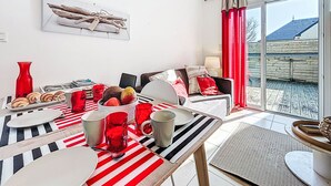 Ein Essbereich mit einem Tisch für zwei Personen, einer roten Vase und einer Obstschale.