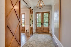 Ein Flur mit Holztür, großem Fenster und einer Chandelier.