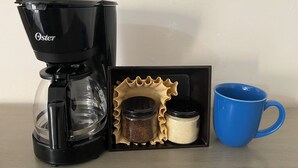 Una cafetera, una caixa amb una tassa blava i dos recipients amb tapa.