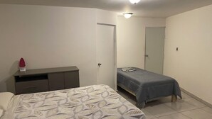 Un dormitori amb llit, una taula de nit, un prestatge i un mirall.