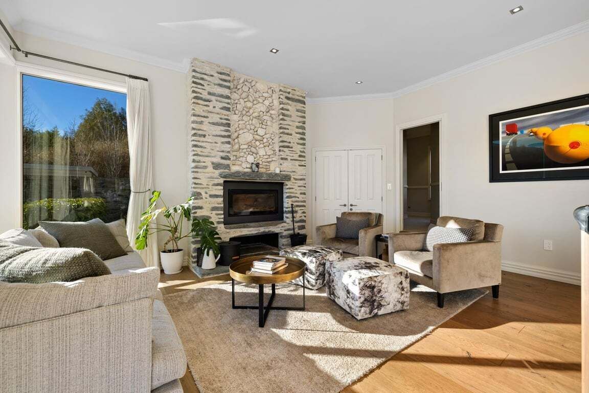 Una sala de estar moderna con chimenea de piedra, asientos cómodos y un ventanal grande.