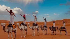 Un grupo de personas montadas en camellos en un desierto bajo un cielo despejado.