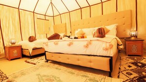 Un dormitorio con una cama grande, dos mesitas de noche y una alfombra estampada.