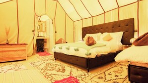 Una habitación tipo tienda de campaña con una cama, un aparador y un espejo.