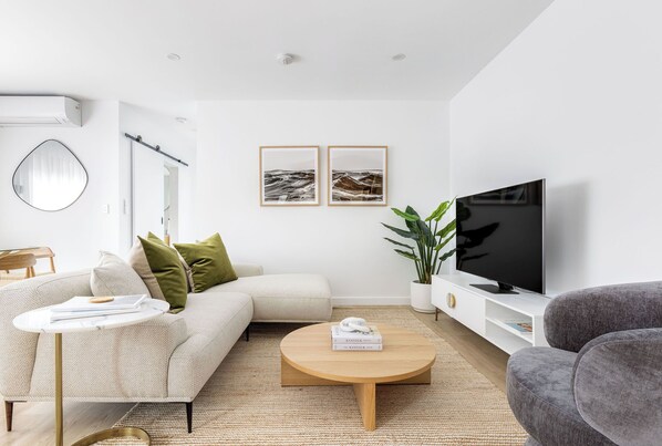 A modern living room with a sofa, coffee table, TV, and artwork on the wall. - Medusa Bondi (Bondi)