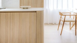 A modern kitchen with a wooden island, a dining area with a table and chairs, and a large window with sheer curtains. - Medusa Bondi (Bondi)