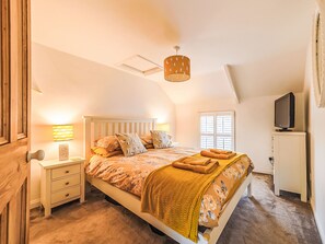Ein Schlafzimmer mit einem Bett, Nachttischen, einer Lampe, einem Fernseher und einem Fenster.