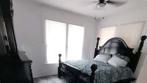 A bedroom with a bed, a ceiling fan, and a window.