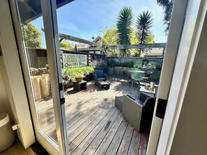 Une terrasse en bois avec des meubles d’extérieur, une enseigne indiquant « Lions, tigres et ours, oh, et des jouets de qualité », et une vue sur le jardin.