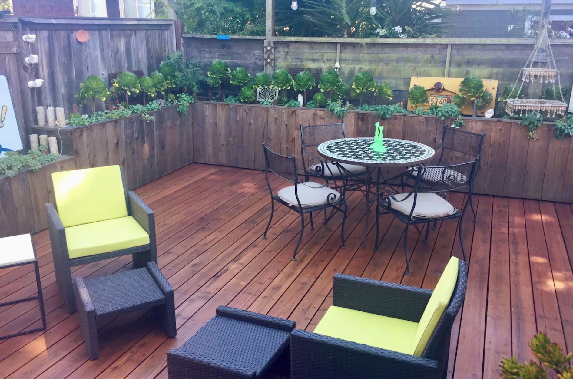 An outdoor patio with a wooden deck, a round table with chairs, and a yellow chair.