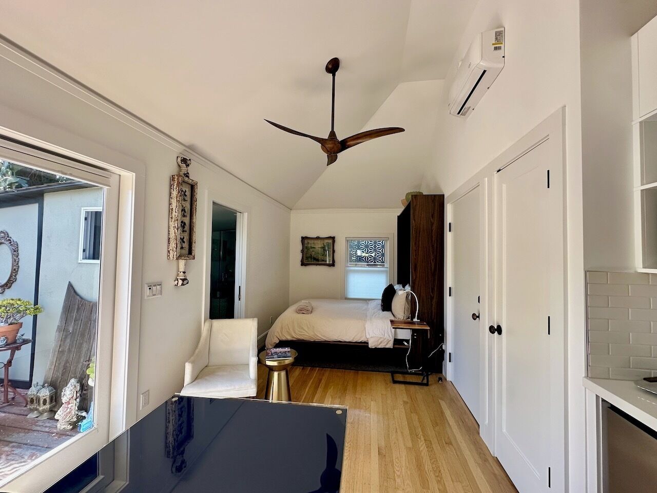 A compact room with a bed, a desk, a ceiling fan, and a window.