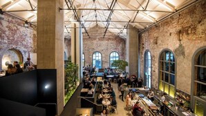 Un restaurante amplio y diáfano con techos altos y paredes de ladrillo visto.