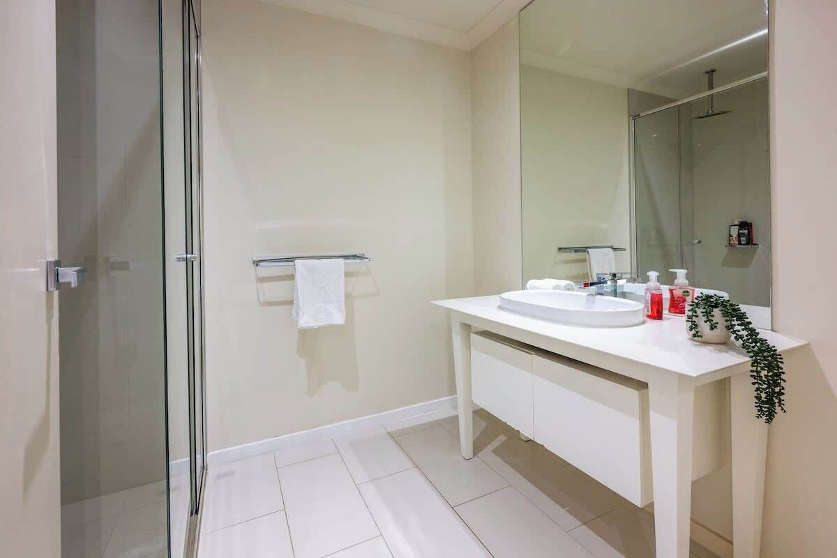 A modern bathroom with a glass shower enclosure, a white sink vanity, and a large mirror.