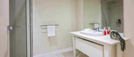 A modern bathroom with a glass shower enclosure, a white sink vanity, and a large mirror.