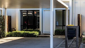 Um edifício moderno com telhado plano, janelas amplas e área de entrada coberta.