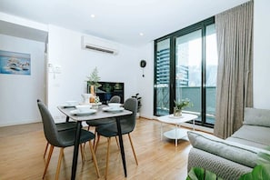 Ein modernes Wohnzimmer mit Essbereich, großen Fenstern und Stadtblick sowie einer gemütlichen Sitzecke.