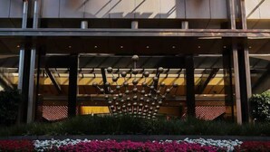 A hotel entrance with a large illuminated 'CROWN' sign, a decorative crown structure, and a flower bed with pink and white flowers. - 5 Min to Crown & NGV | Stylish 2BR | City View (Southbank)