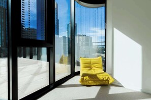 A modern room with large windows offering a city view, a yellow cushioned bench, and a clean, minimalist design. - Melbourne Southbank FreeCarPark & Amazing Pool (Southbank)