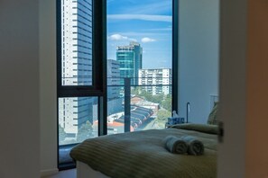 A hotel room with a large window offering a view of modern buildings and a parking lot. - Melbourne Southbank FreeCarPark & Amazing Pool (Southbank)