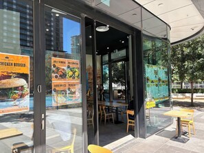 An outdoor dining area with glass walls, wooden tables, and chairs. - Melbourne Southbank FreeCarPark & Amazing Pool (Southbank)