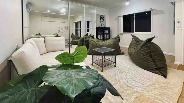 A modern living room with a sofa, bean bag chairs, a coffee table, and large green plants. - Puddings Home Wheelers Hill A/C WiFi Garden (Wheelers Hill)
