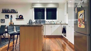 A modern kitchen with a wooden island, white cabinets, and stainless steel appliances. - Puddings Home Wheelers Hill A/C WiFi Garden (Wheelers Hill)