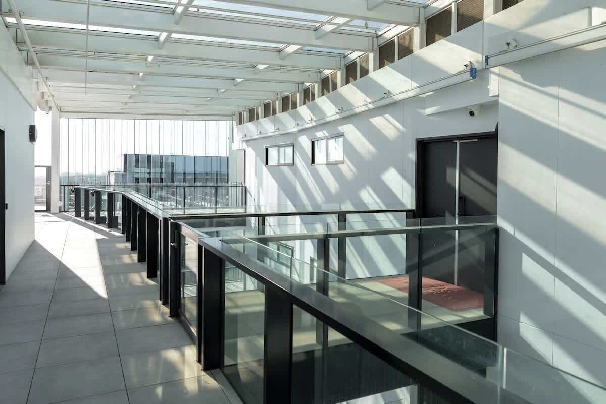 A modern interior with a glass railing, a staircase, and a view of the city.