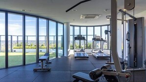 Ein modernes Fitnessstudio mit großen Fenstern, Laufbändern und Krafttrainingsgeräten.