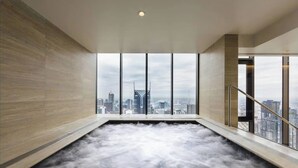 Una piscina interior moderna con vistas a la ciudad a través de amplios ventanales.
