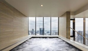 A modern indoor pool with a cityscape view through large windows. - Puddings Home Designer City Views & Balcony (Melbourne)