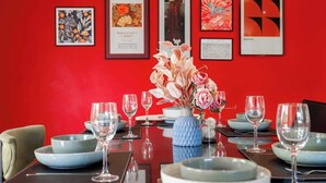 Une table à manger dressée avec des assiettes, des bols et des verres à vin, entourée de chaises.
