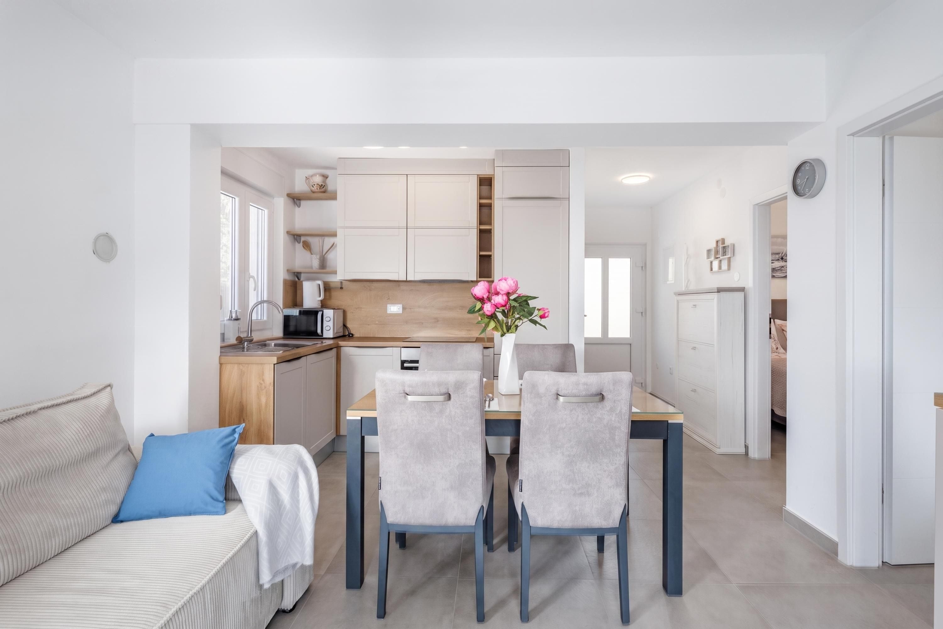 A modern kitchen with white cabinets, a wooden countertop, and a dining area with a table and chairs.