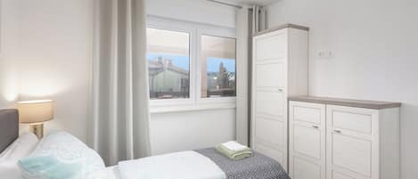 A bedroom with a bed, a wardrobe, a window, and a lamp.