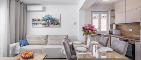 A modern kitchen with a dining area, a sofa, and a painting on the wall.