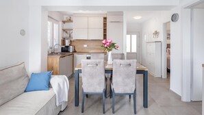 A modern kitchen with white cabinets, a wooden countertop, and a dining area with a table and chairs. - Susi's Holiday Home (Medulin)