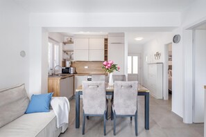 A modern kitchen with white cabinets, a wooden countertop, and a dining area with a table and chairs. - Susi's Holiday Home (Medulin)