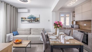 A modern kitchen with a dining area, a sofa, and a painting on the wall. - Susi's Holiday Home (Medulin)