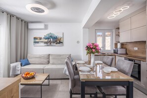 A modern kitchen with a dining area, a sofa, and a painting on the wall. - Susi's Holiday Home (Medulin)