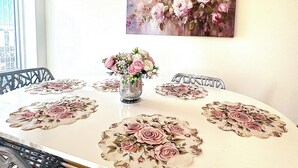 Una mesa de comedor con manteles individuales estampados con flores, un florero y un cuadro de flores en la pared.