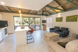 Eine moderne Küche mit Kochinsel, ein Essbereich mit einer Couch und ein Wohnzimmer mit blauem Sofa und Couchtisch.