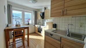 Una cocina compacta con armarios de madera, horno empotrado, un lavabo y una ventana con persianas.
