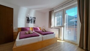 Un dormitorio moderno con una cama plataforma de madera, dos almohadas, una colcha, una mesita de noche, una lámpara y un cuadro en la pared.
