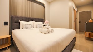 A neatly made bed with a dark headboard, a small bedside table, and a wall-mounted light fixture. - Miami Seaview (La-ngu)